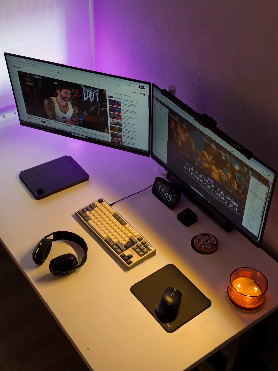Escritorio de trabajo de moca® con dos monitores, teclado mecánico y una vela encendida bajo luz violeta